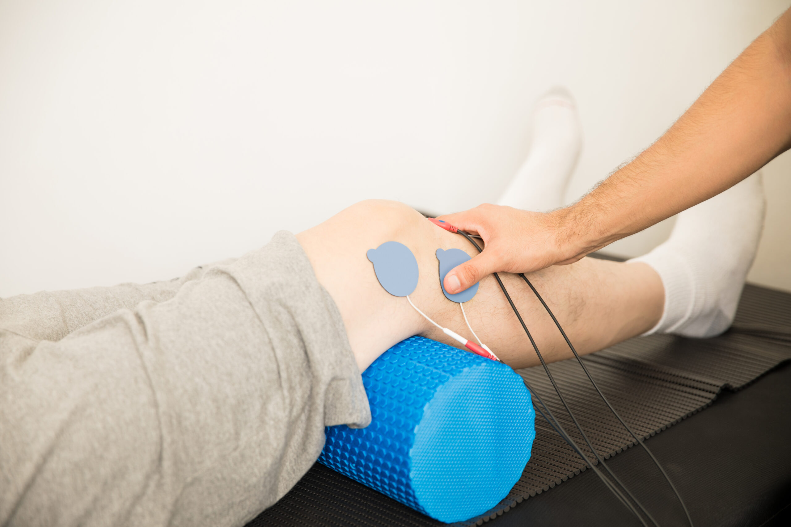 Physiotherapist’s Hand Positioning Electrodes On Patient’s Knee